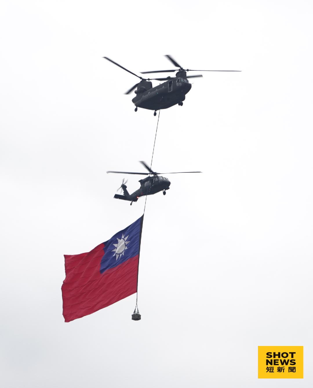 CH-47SD運輸直升機吊掛巨幅國旗伴隨UH-60M通用直升機飛越府前廣場（謝亦然攝影）