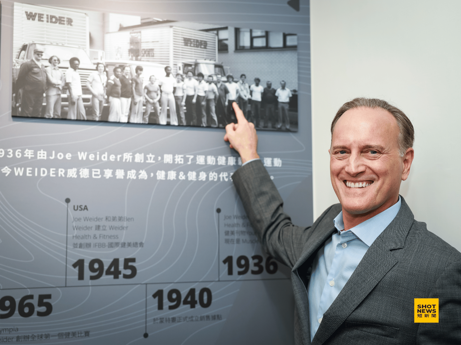 威德董事長 Eric Weider 指出當年在工廠前與員工們一起合影的自己。