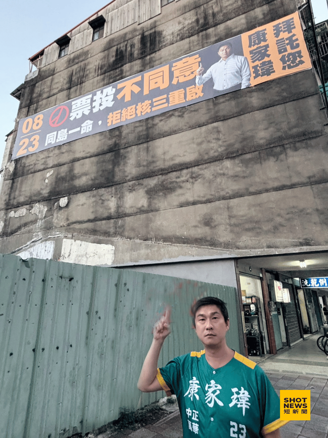台北市議員參選人康家瑋與自己懸掛的反對核三重啟公投布條。（康家瑋提供)