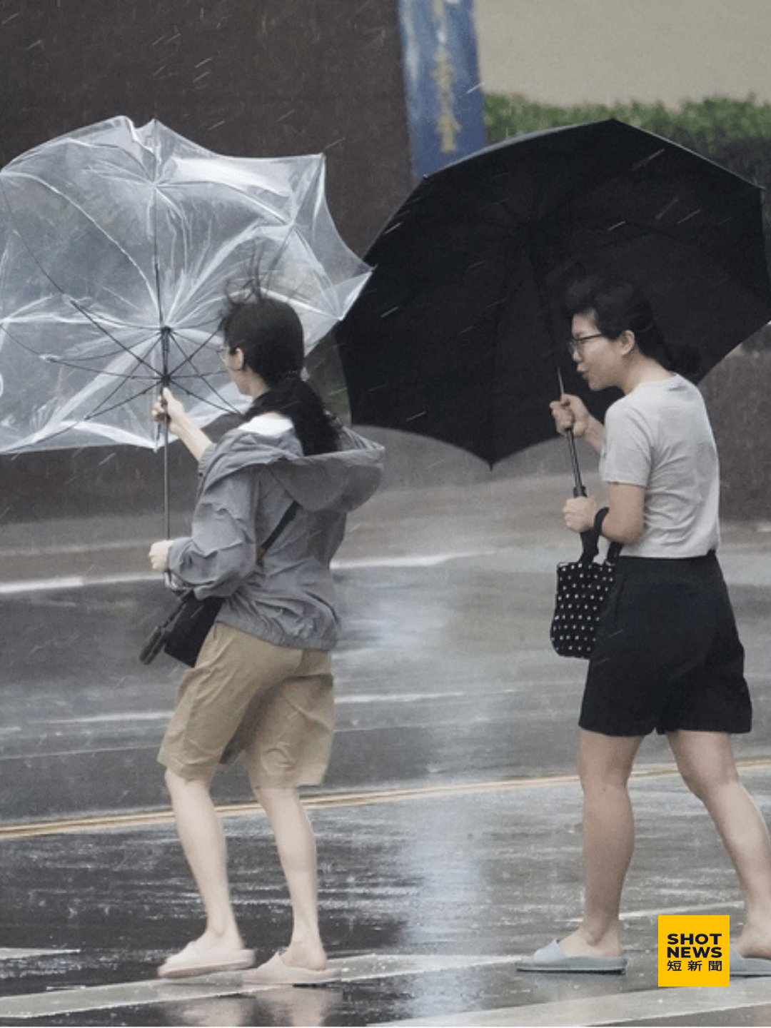 颱風進逼現風雨行人撐傘開花。(中央社)